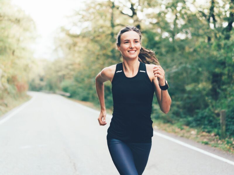 Woman running along a tree lined road