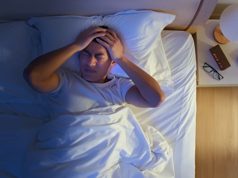 Man in bed with a headache or migraine